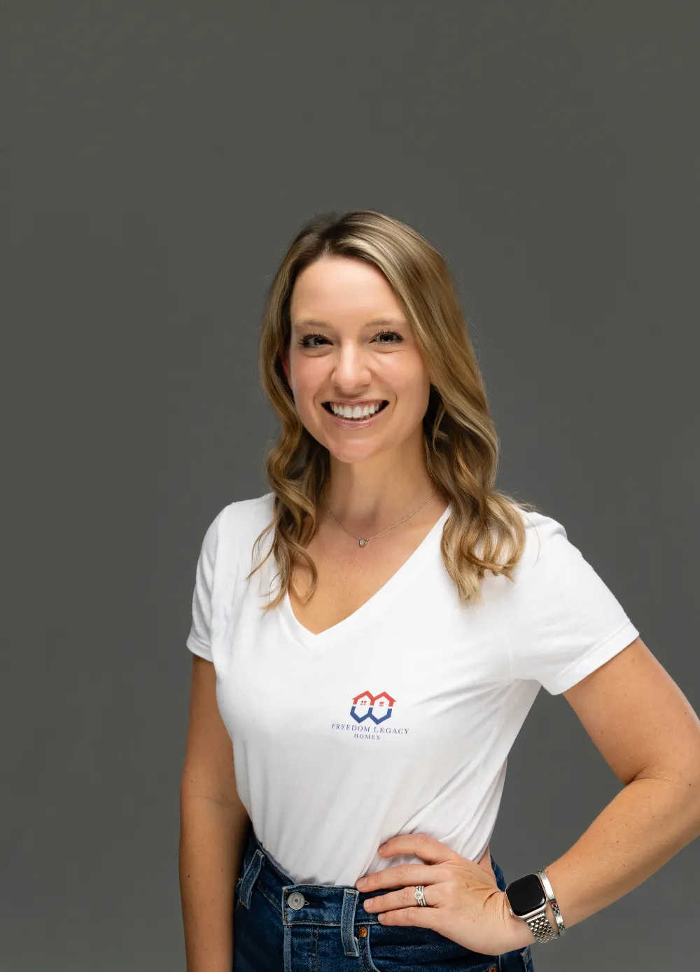 Professional headshot of a smiling female real estate expert in a white V-neck shirt.
